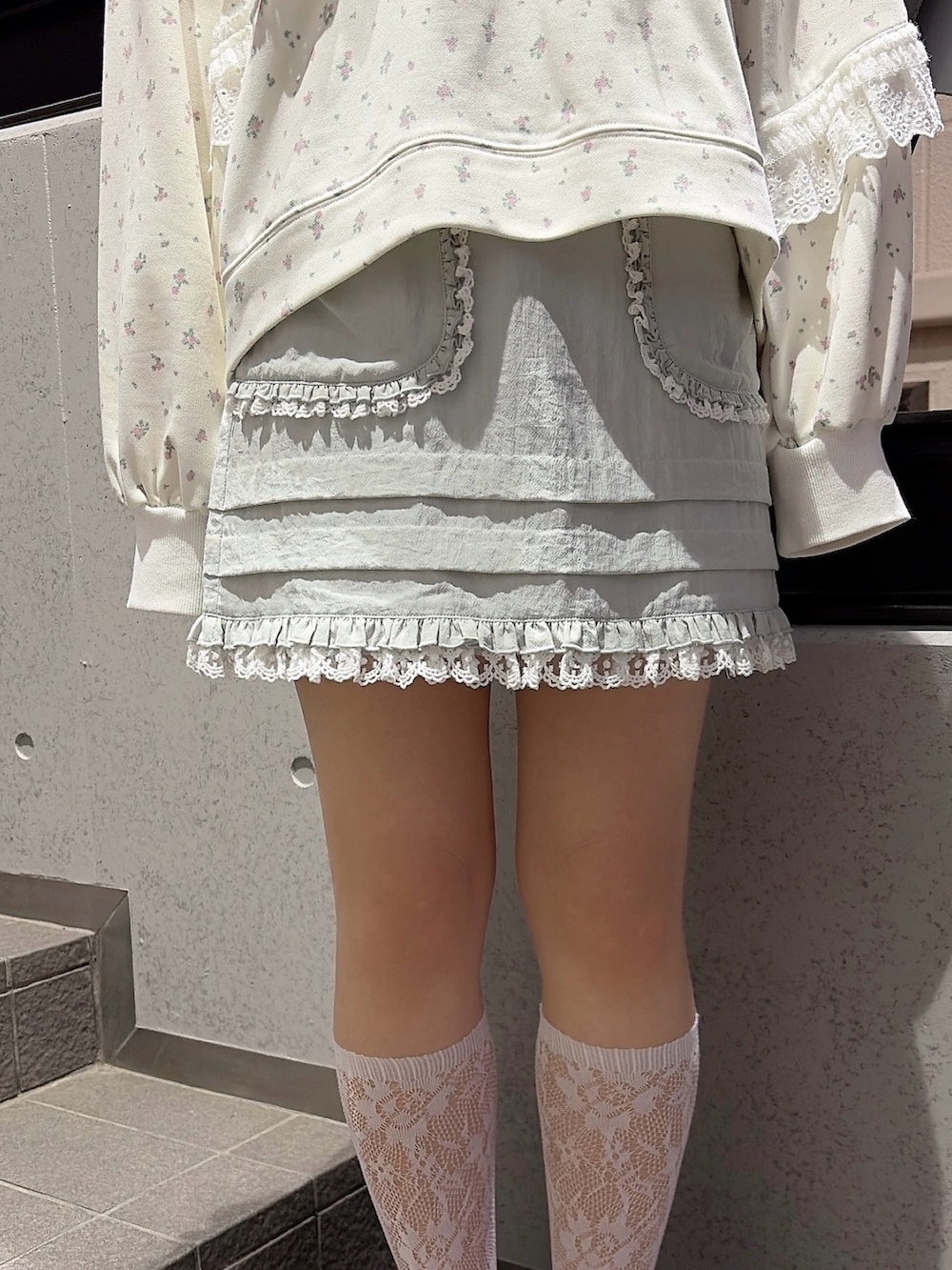 ホワイト系のスウェット、ブルー系のスカート、ブラック系のスニーカーを着用したレディースの冬コーディネートの6枚目の写真