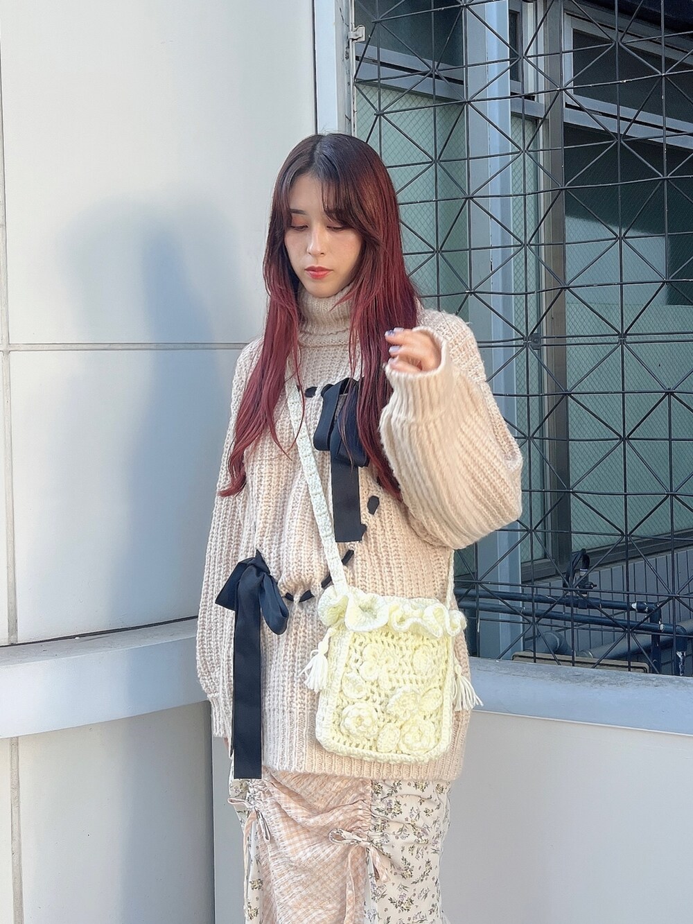 ホワイト系のハンドバッグ、ホワイト系のニット/セーター、ホワイト系のスカートを着用したレディースの秋コーディネートの2枚目の写真