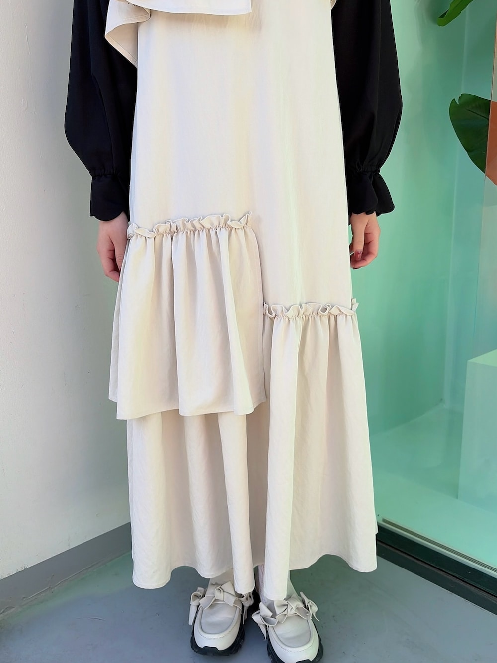 ベージュ系のワンピース、ブラック系のシャツ/ブラウス、ホワイト系のスニーカーを着用したレディースの冬コーディネートの6枚目の写真