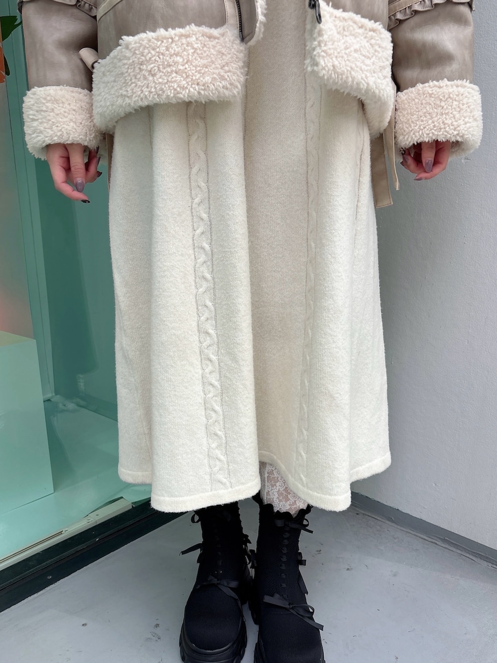 ベージュ系のムートンコート、ホワイト系のワンピース、ブラック系のブーツを着用したレディースの秋コーディネートの6枚目の写真