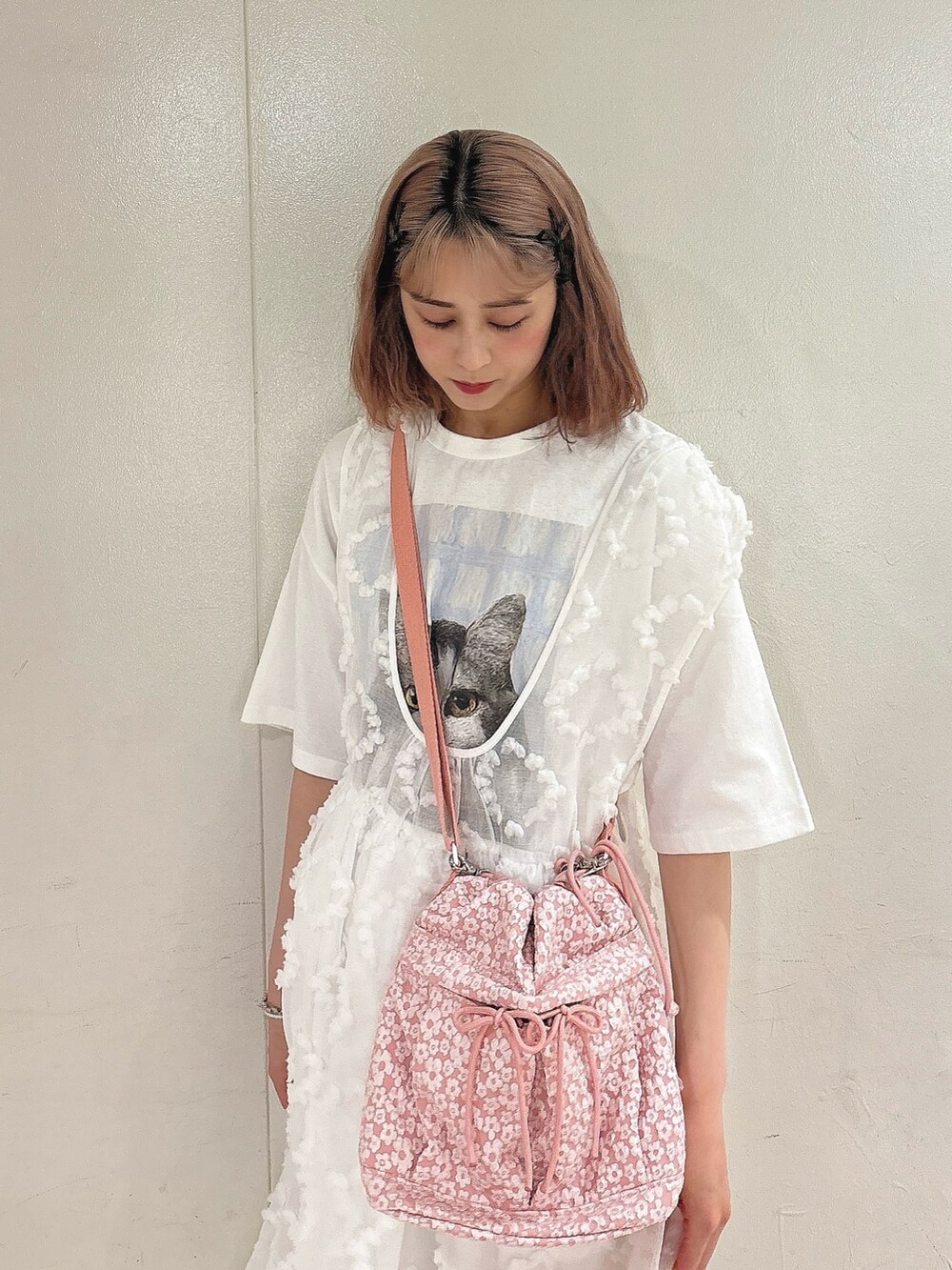 ピンク系のショルダーバッグ、ホワイト系のジャンパースカート、ホワイト系のTシャツ/カットソーを着用したレディースの夏コーディネートの3枚目の写真