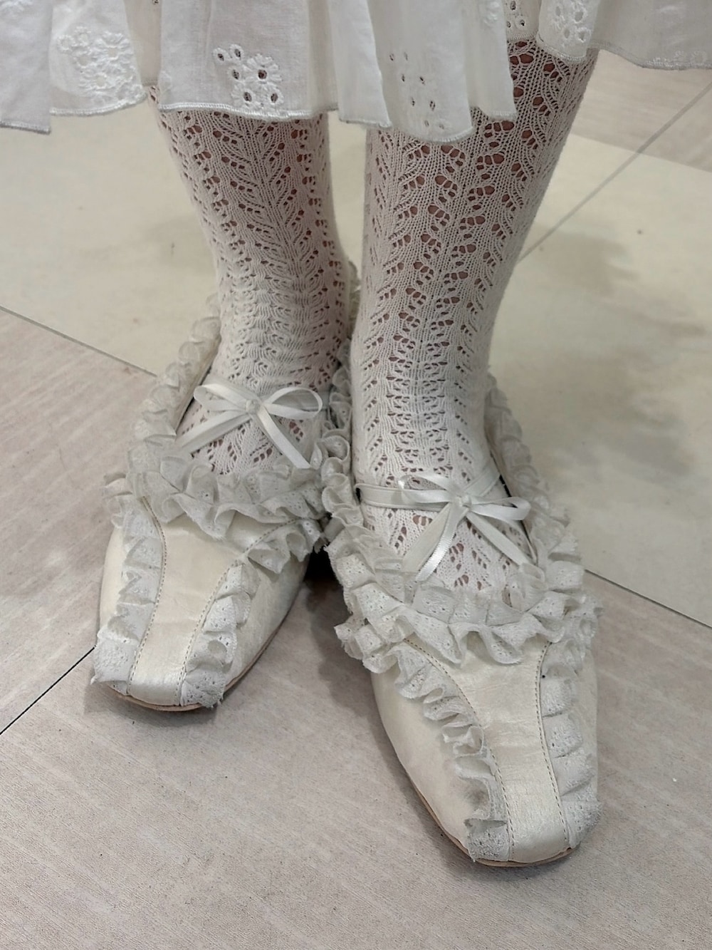 ホワイト系のポロシャツ、ホワイト系のワンピース、ホワイト系のショルダーバッグを着用したレディースの冬コーディネートの7枚目の写真