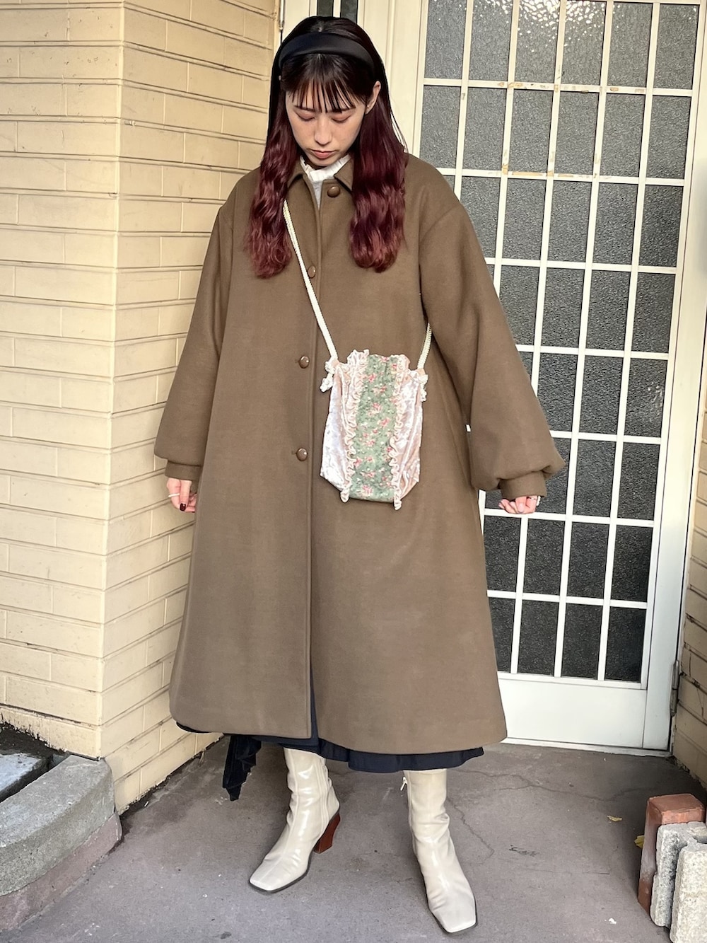 グリーン系のステンカラーコート、ブラック系のスカート、ベージュ系のブーツを着用したレディースの冬コーディネートの2枚目の写真