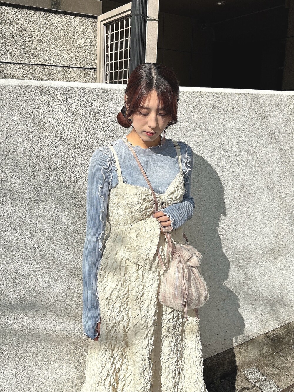 ピンク系のショルダーバッグ、ベージュ系のワンピース、ブルー系のTシャツ/カットソーを着用したレディースの冬コーディネートの2枚目の写真