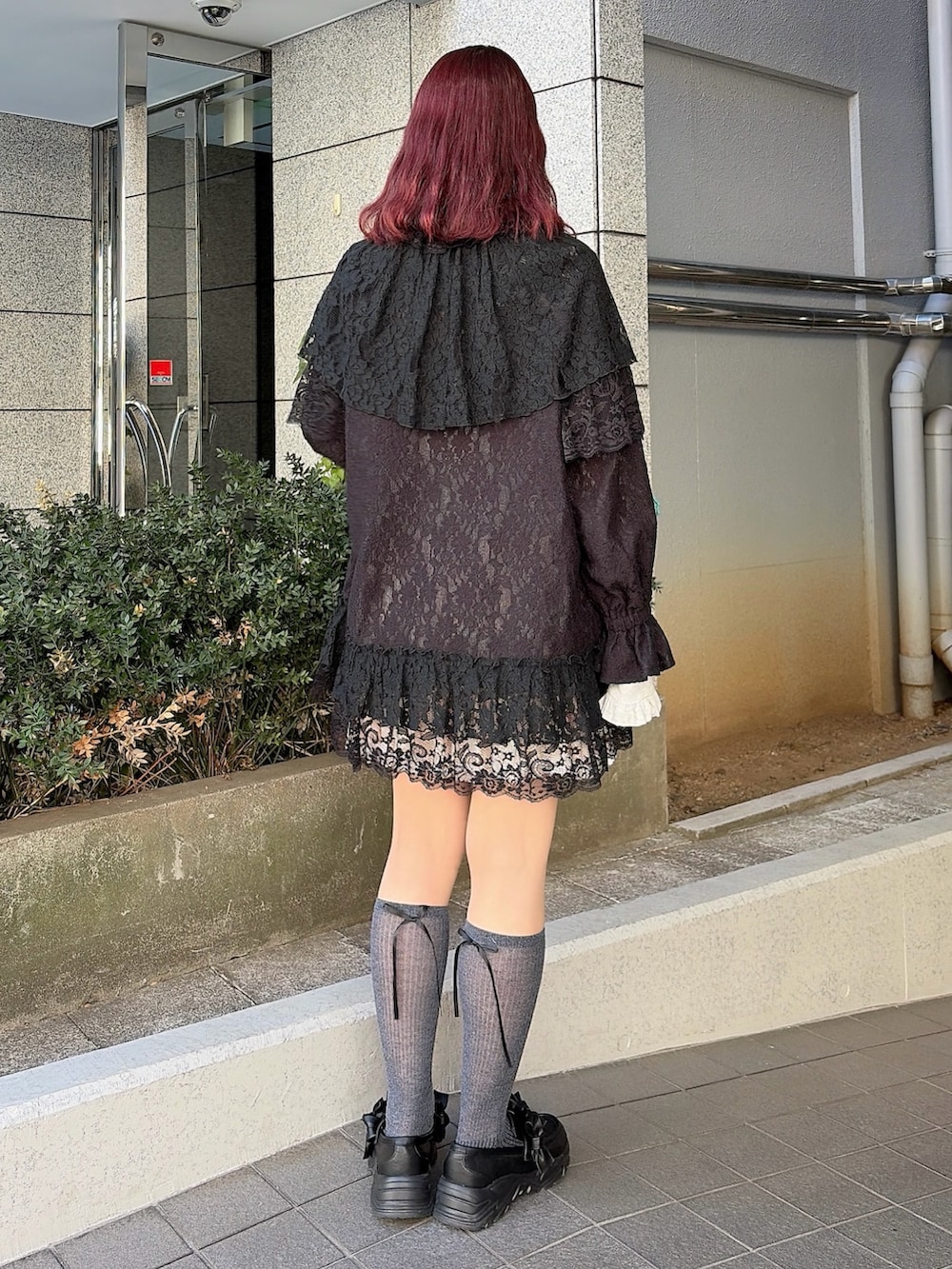 ブラック系のテーラードジャケット、ピンク系のスカート、ブラック系のスニーカーを着用したレディースの冬コーディネートの2枚目の写真