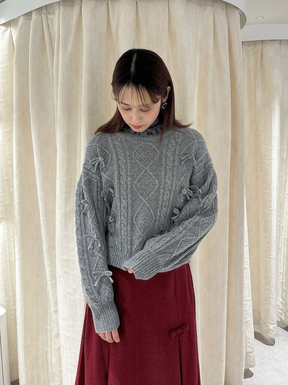 グレー系のニット/セーター、レッド系のスカート、ホワイト系のローファーを着用したレディースの秋コーディネートの3枚目の写真