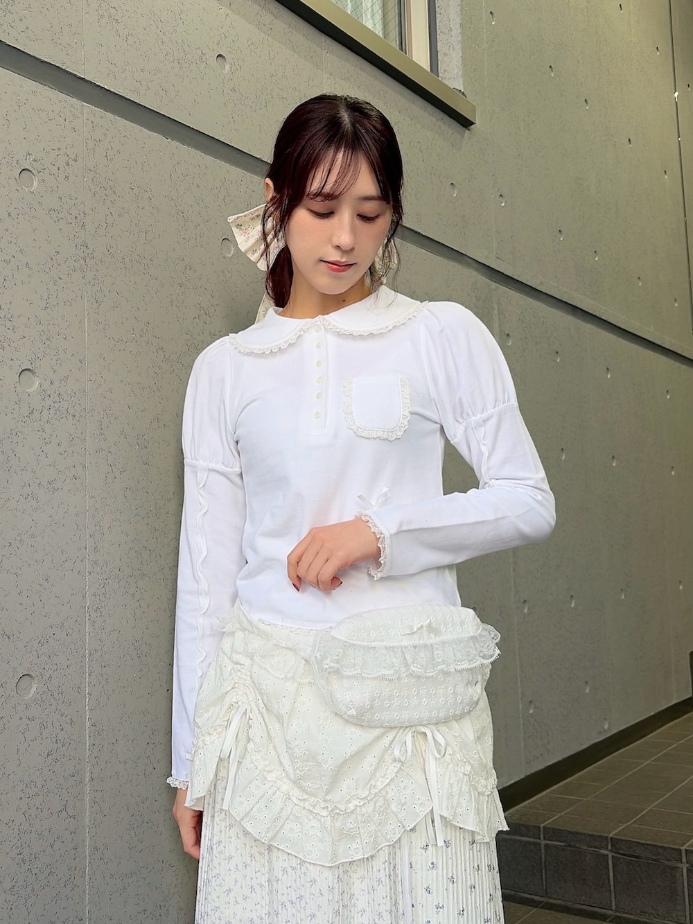 ホワイト系のポロシャツ、ホワイト系のボディバッグ/ウエストポーチ、ホワイト系のスカートを着用したレディースの冬コーディネートの3枚目の写真