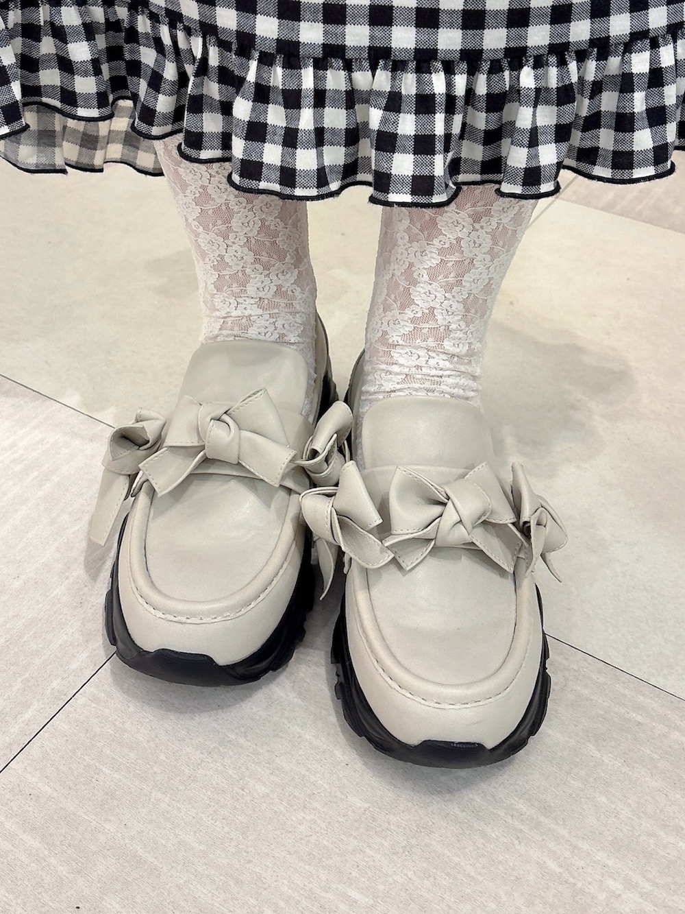 グレー系のパーカー、ブラック系のスカート、ホワイト系のスニーカーを着用したレディースの秋コーディネートの7枚目の写真