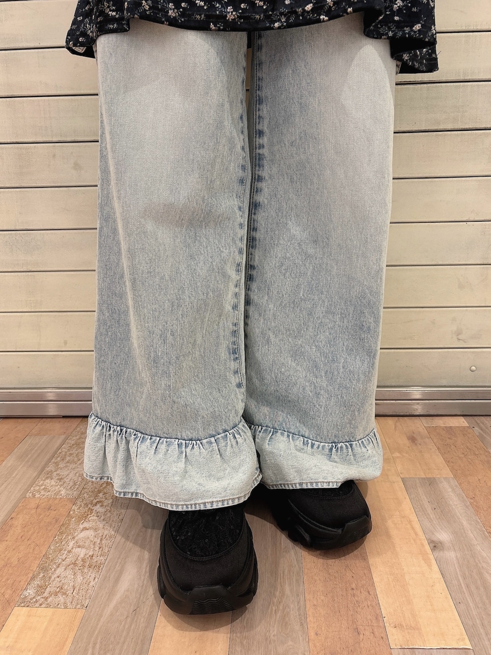 ブラック系のワンピース、ブルー系のデニムパンツ、ブラック系のスニーカーを着用したレディースの秋コーディネートの6枚目の写真