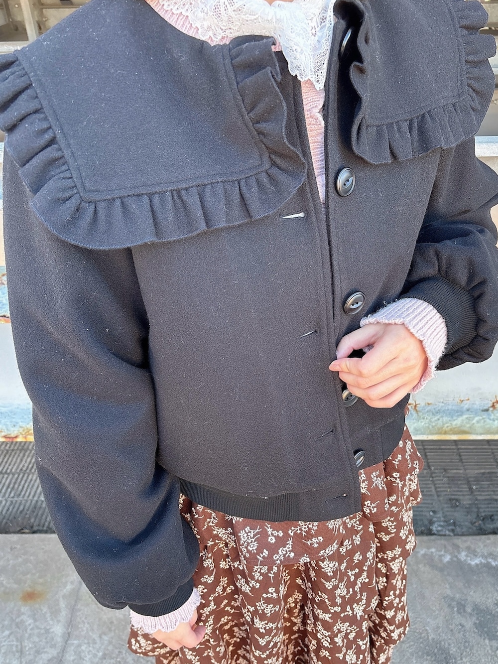 ブラウン系のワンピース、ブラック系のパンプス、ピンク系のカーディガン/ボレロを着用したレディースの冬コーディネートの5枚目の写真