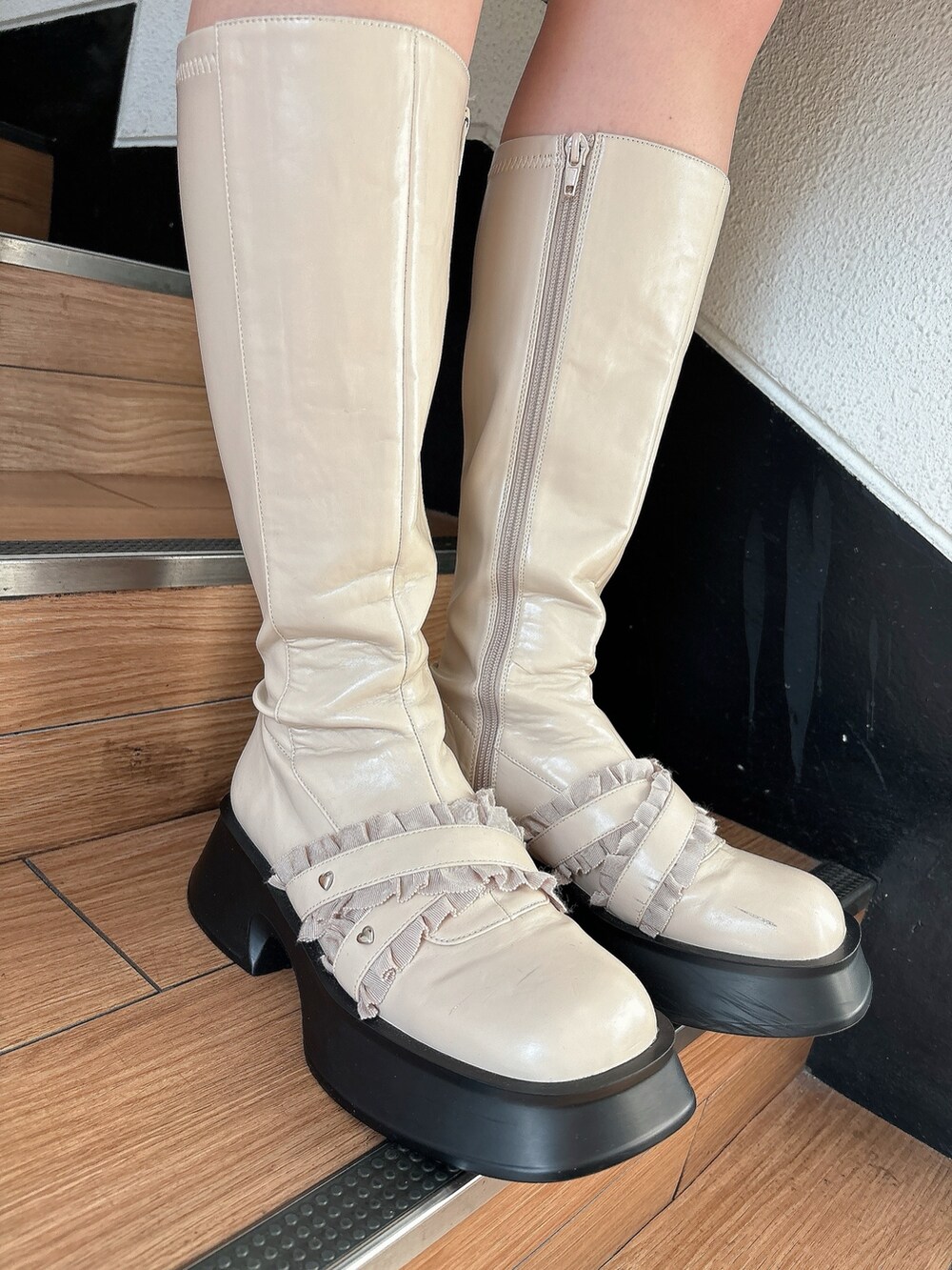 ブラック系のチェスターコート、ホワイト系のブーツ、ブラック系のニット/セーターを着用したレディースの秋コーディネートの5枚目の写真