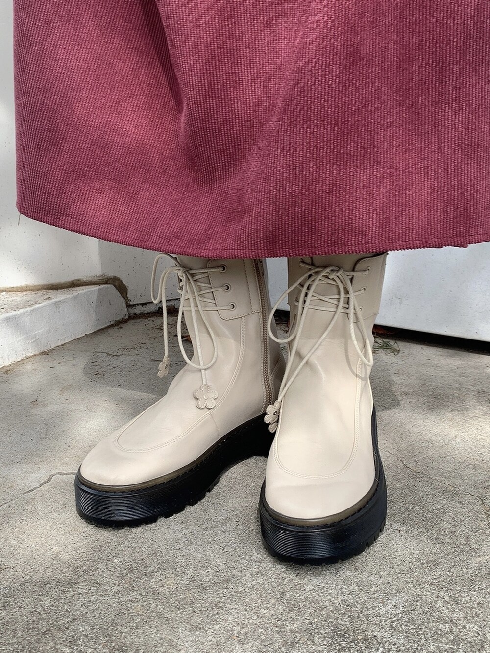 ブラウン系のカバーオール、ホワイト系のブーツ、ホワイト系のショルダーバッグを着用したレディースの秋コーディネートの4枚目の写真