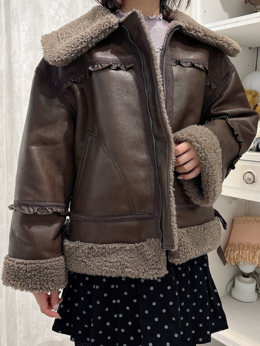 ブラウン系のムートンコート、パープル系のニット/セーター、ブラック系のスカートを着用したレディースの秋コーディネートの5枚目の写真