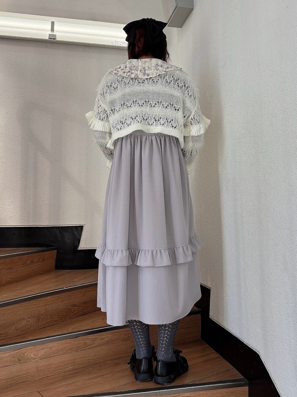 ホワイト系のカーディガン/ボレロ、パープル系のワンピース、ブラック系のパンプスを着用したレディースの秋コーディネートの2枚目の写真
