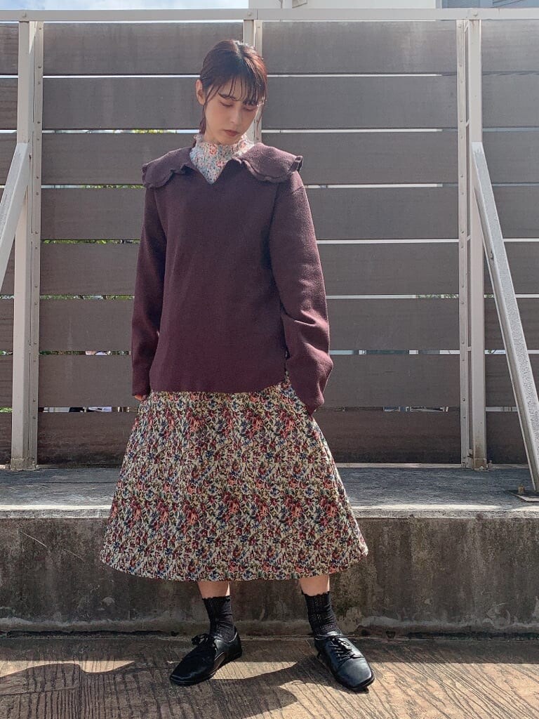 ブラウン系のニット/セーター、グリーン系のチェスターコート、レッド系のスカートを着用したレディースの秋コーディネートの2枚目の写真