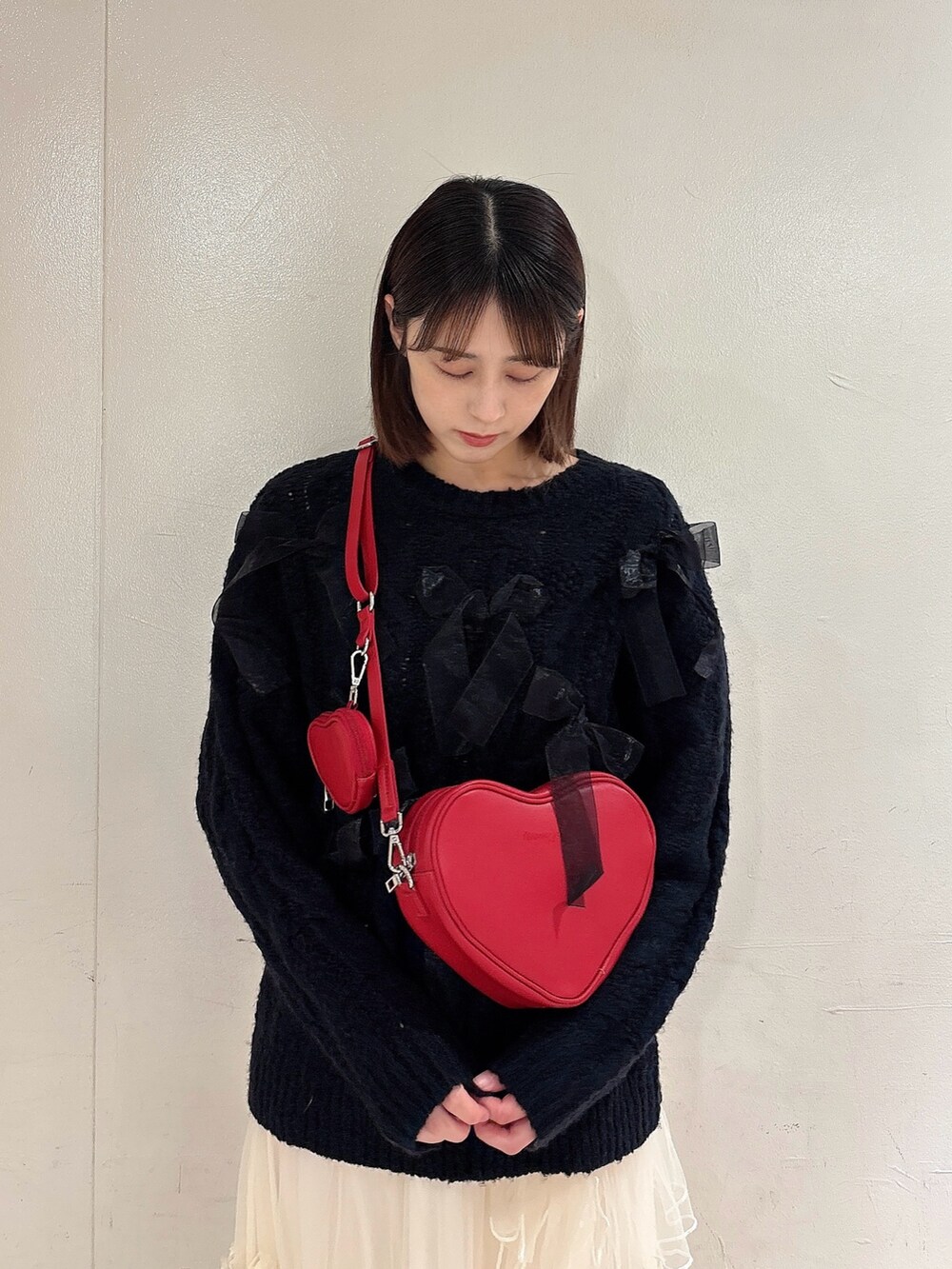 ブラック系のニット/セーター、レッド系のショルダーバッグ、ホワイト系のスカートを着用したレディースの冬コーディネートの3枚目の写真