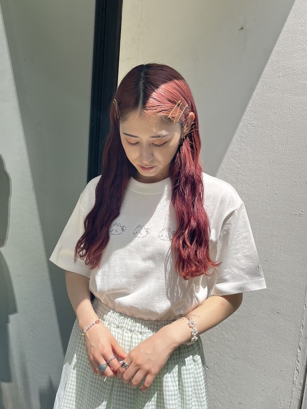 グリーン系のスカート、ホワイト系のスニーカー、ホワイト系のTシャツ/カットソーを着用したレディースの夏コーディネートの2枚目の写真