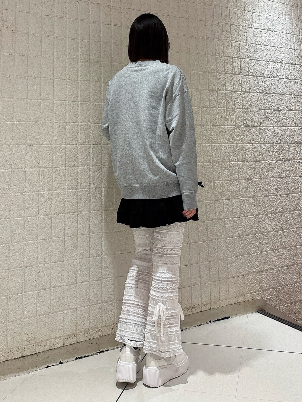 グレー系のスウェット、ブラック系のスカート、ホワイト系のその他パンツを着用したレディースの冬コーディネートの2枚目の写真