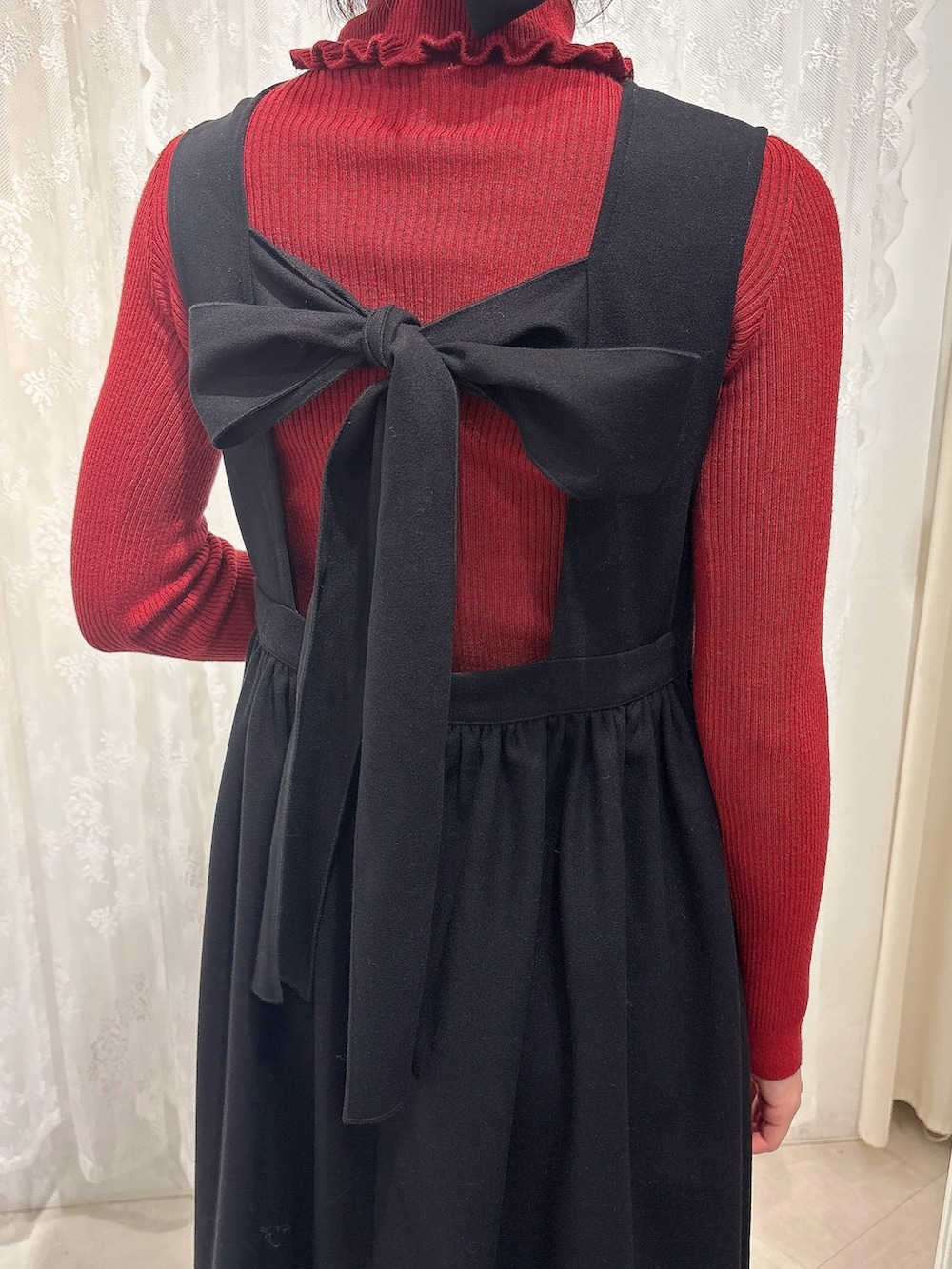 レッド系のニット/セーター、ベージュ系のショルダーバッグ、ブラック系のワンピースを着用したレディースの秋コーディネートの6枚目の写真
