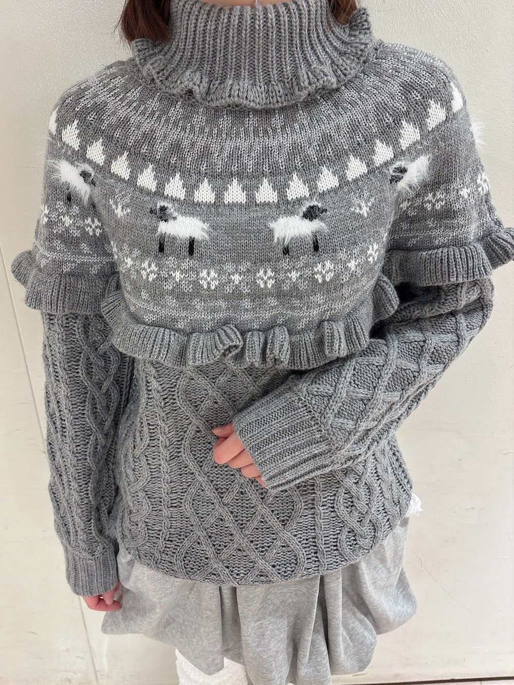 グレー系のニット/セーター、グレー系のスカート、ホワイト系のその他パンツを着用したレディースの冬コーディネートの5枚目の写真