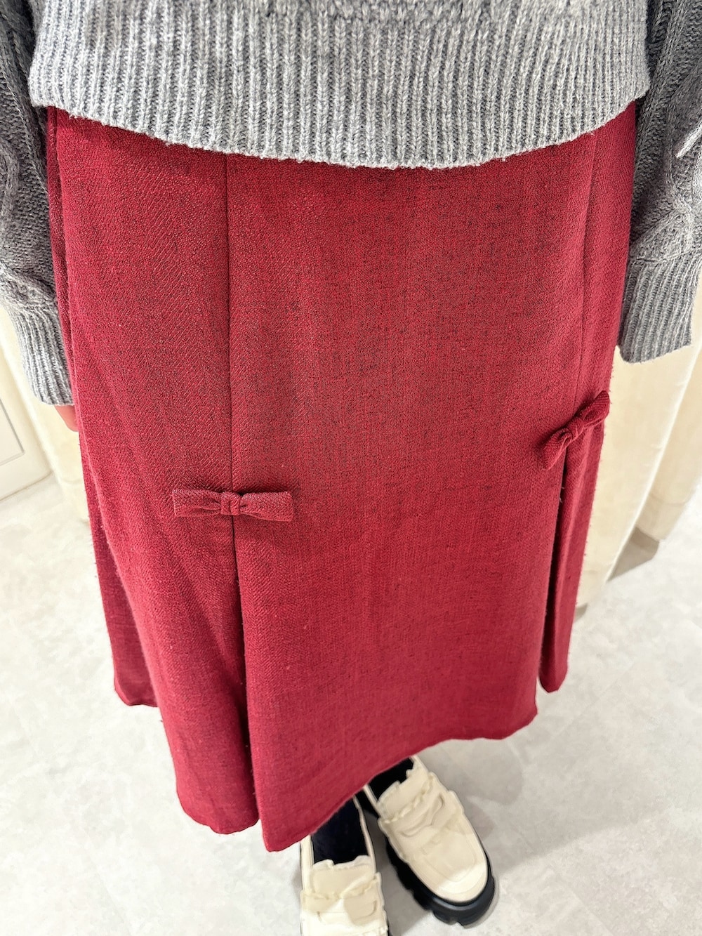 グレー系のニット/セーター、レッド系のスカート、ホワイト系のローファーを着用したレディースの秋コーディネートの6枚目の写真