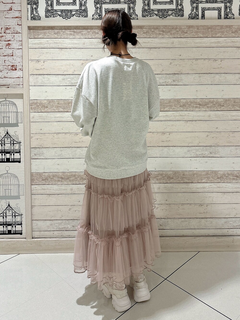 ピンク系のスカート、グレー系のスウェット、ホワイト系のスニーカーを着用したレディースの秋コーディネートの2枚目の写真