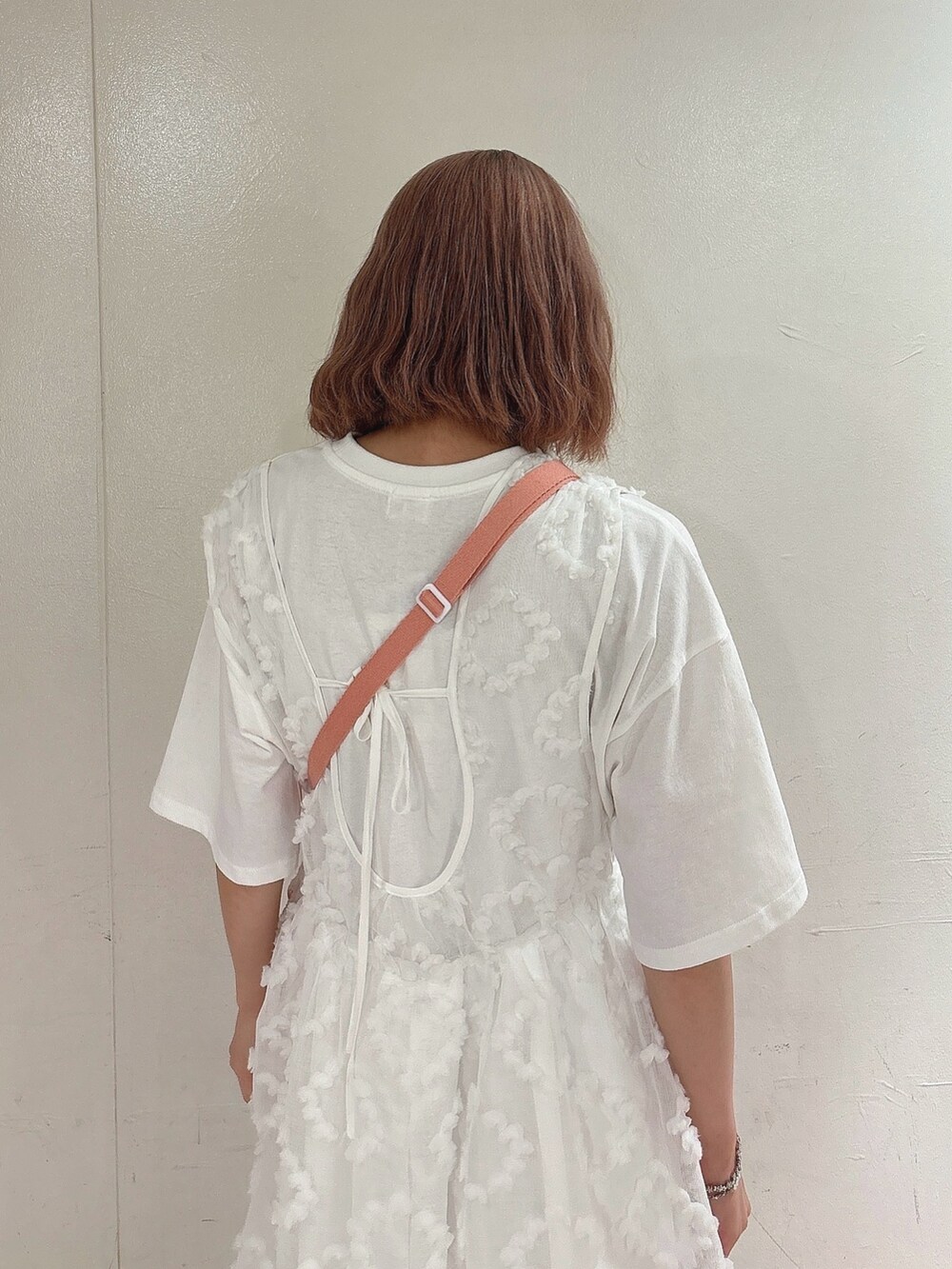 ピンク系のショルダーバッグ、ホワイト系のジャンパースカート、ホワイト系のTシャツ/カットソーを着用したレディースの夏コーディネートの4枚目の写真