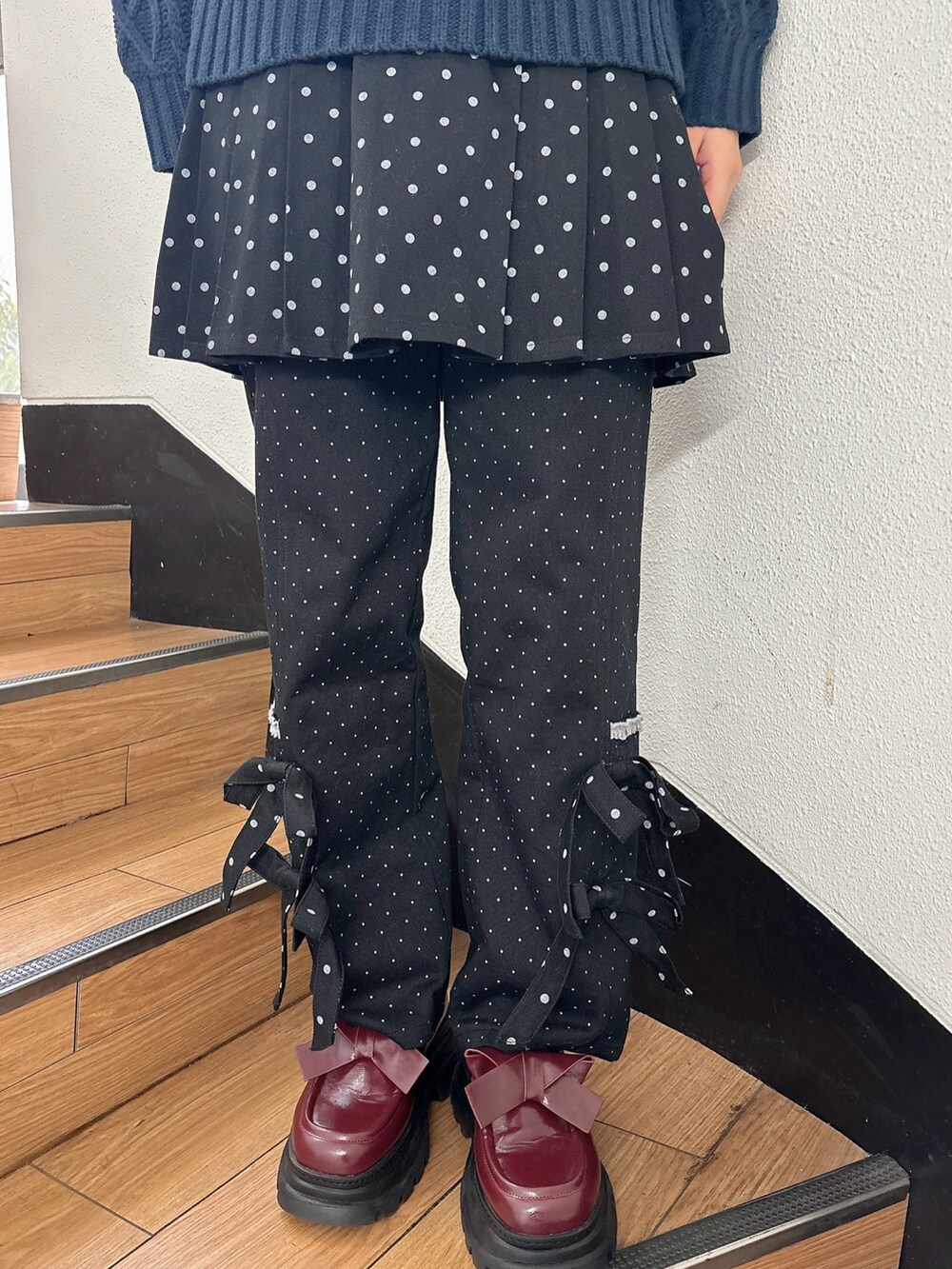 ブルー系のニット/セーター、ブラック系のスラックス、ブラック系のスカートを着用したレディースの秋コーディネートの6枚目の写真