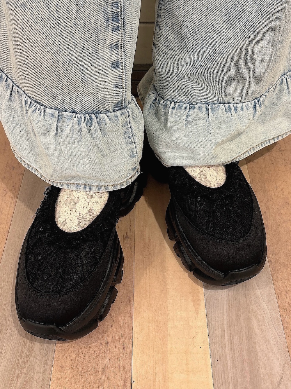 ブラック系のワンピース、ブルー系のデニムパンツ、ブラック系のスニーカーを着用したレディースの秋コーディネートの7枚目の写真