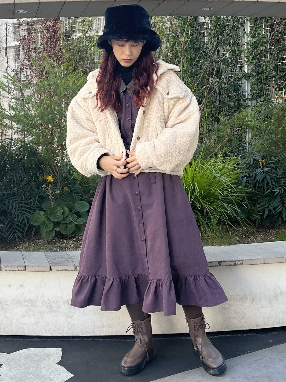 パープル系のワンピース、ブラウン系のブーツ、ブラック系のニット/セーターを着用したレディースの冬コーディネートの2枚目の写真