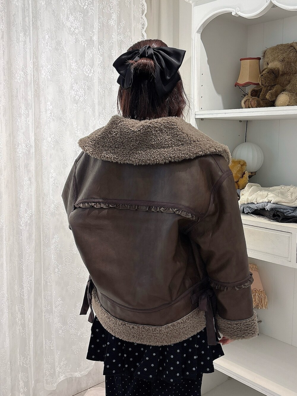 ブラウン系のムートンコート、パープル系のニット/セーター、ブラック系のスカートを着用したレディースの秋コーディネートの4枚目の写真