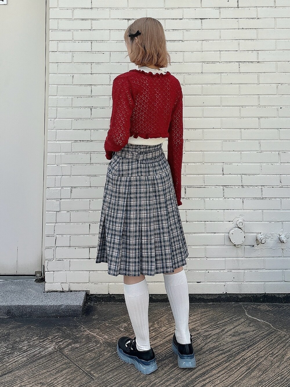 ブラウン系のスカート、ブラック系のスニーカー、ホワイト系のTシャツ/カットソーを着用したレディースの春コーディネートの2枚目の写真