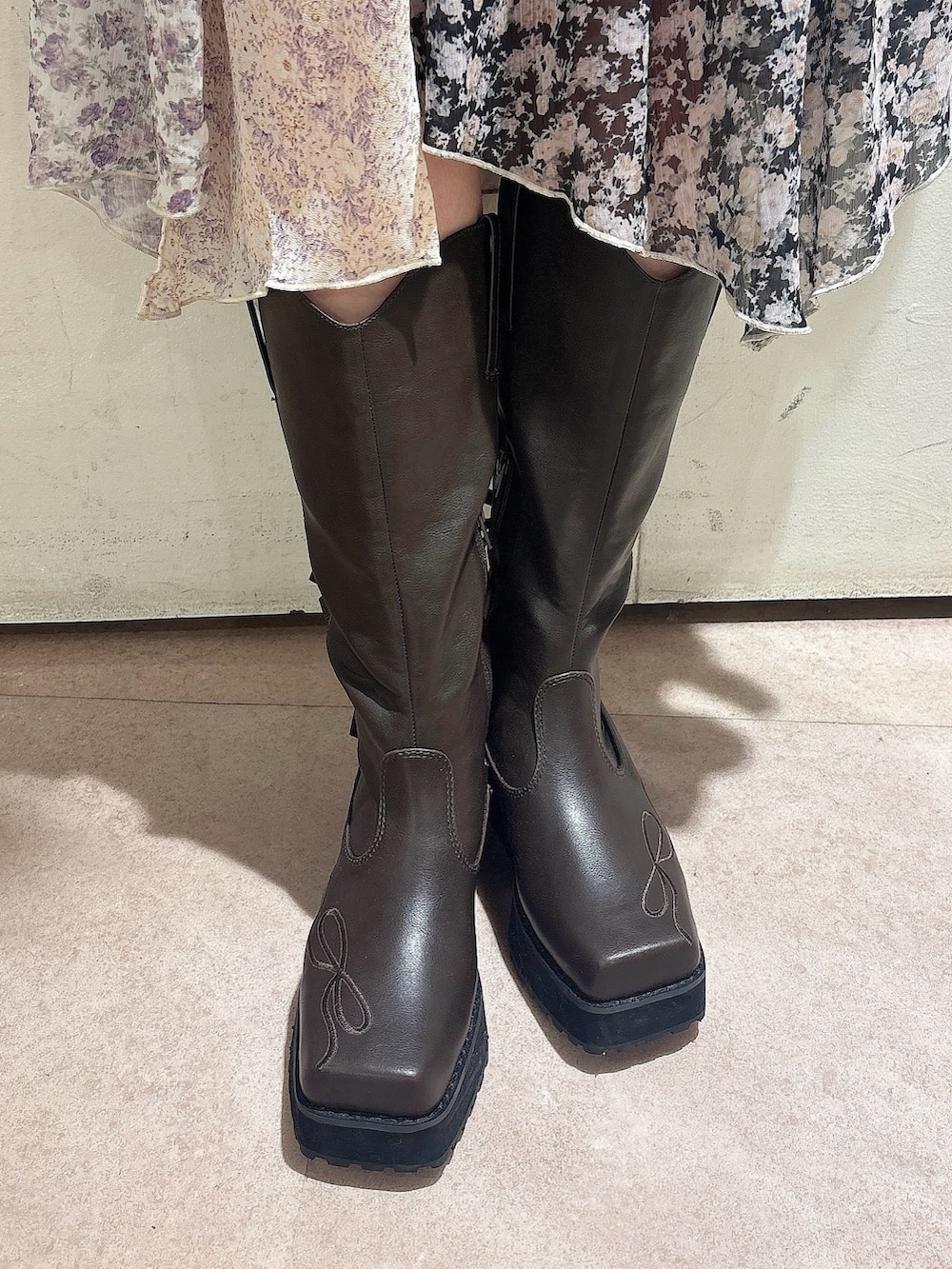 レッド系のスウェット、ブラック系のスカート、ブラウン系のブーツを着用したレディースの秋コーディネートの7枚目の写真