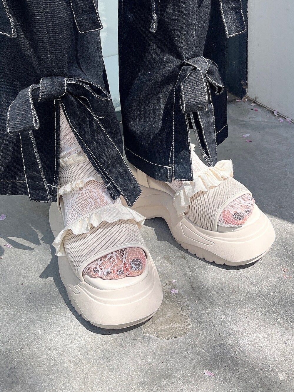 ブラック系のデニムパンツ、ホワイト系のサンダル、ブルー系のニット/セーターを着用したレディースの春コーディネートの3枚目の写真