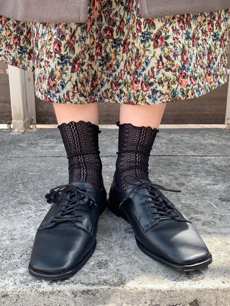 ブラウン系のニット/セーター、グリーン系のチェスターコート、レッド系のスカートを着用したレディースの秋コーディネートの4枚目の写真