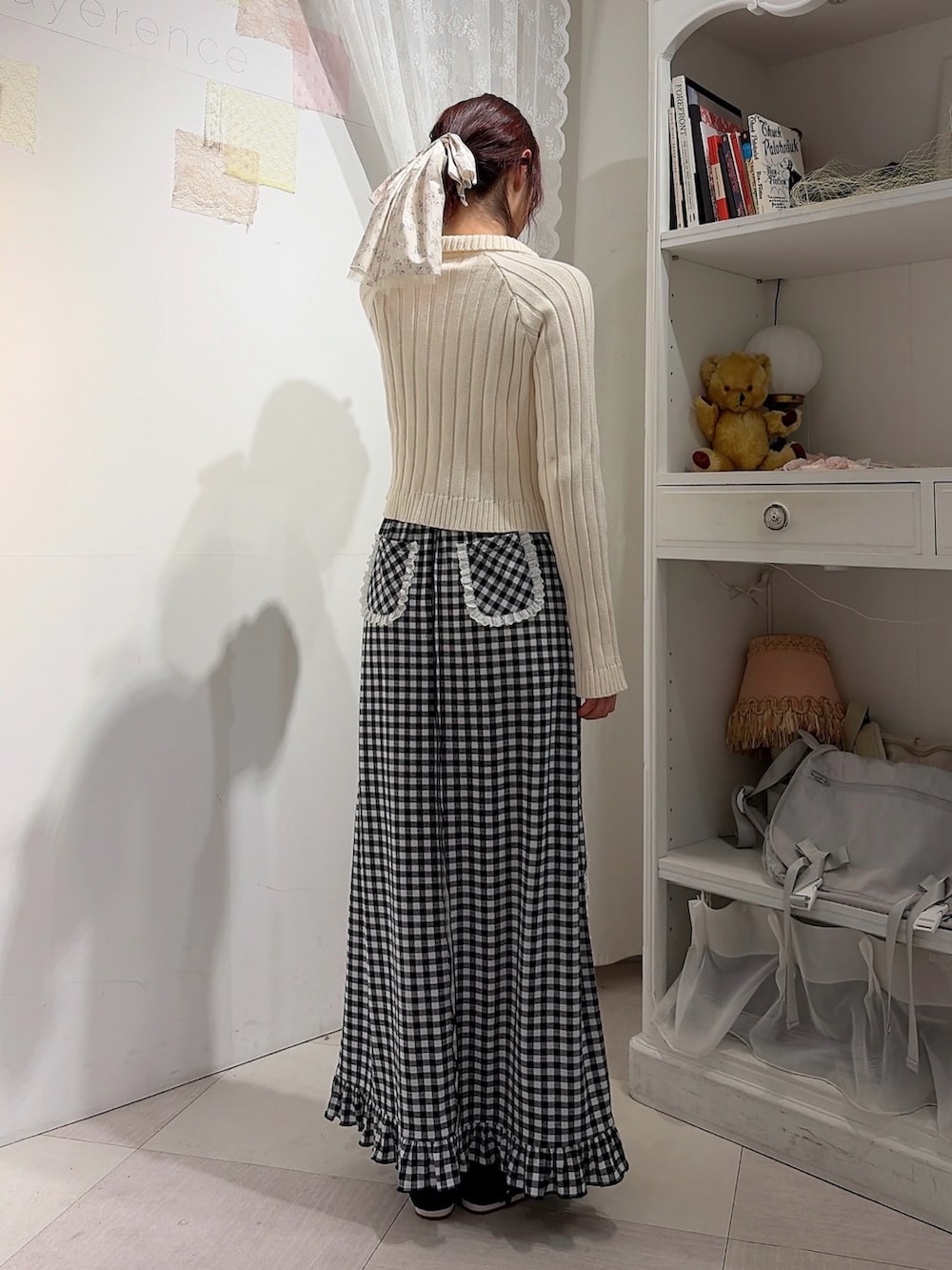 ホワイト系のカーディガン/ボレロ、ブラック系のスカート、ブラック系のスニーカーを着用したレディースの冬コーディネートの2枚目の写真