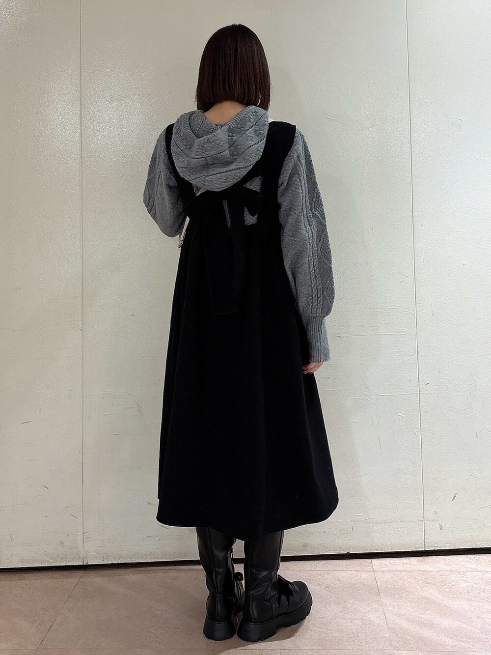 グレー系のニット/セーター、ブラック系のワンピース、ブラック系のブーツを着用したレディースの冬コーディネートの2枚目の写真