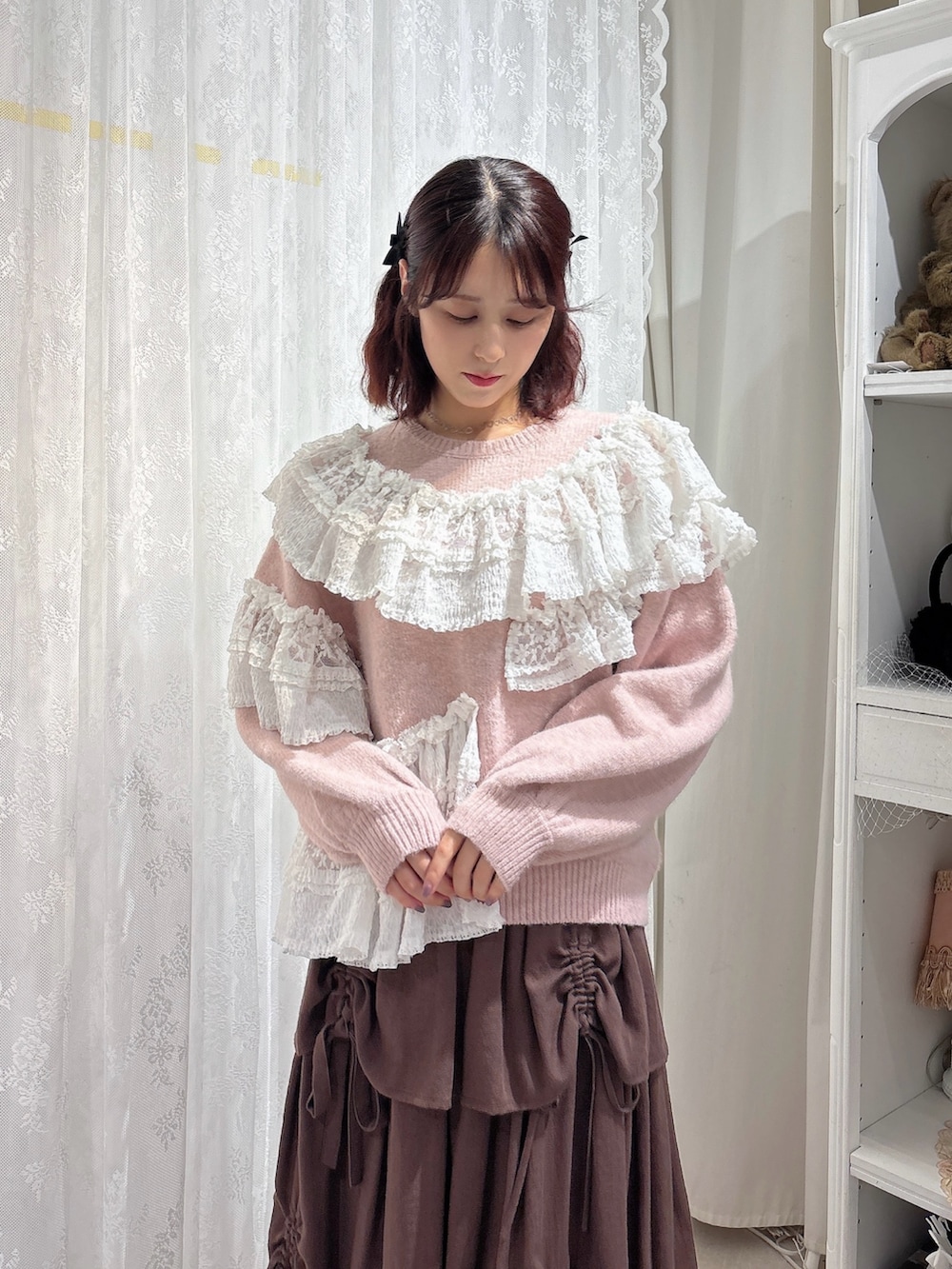 ピンク系のニット/セーター、ホワイト系のショルダーバッグ、ブラウン系のスカートを着用したレディースの秋コーディネートの3枚目の写真