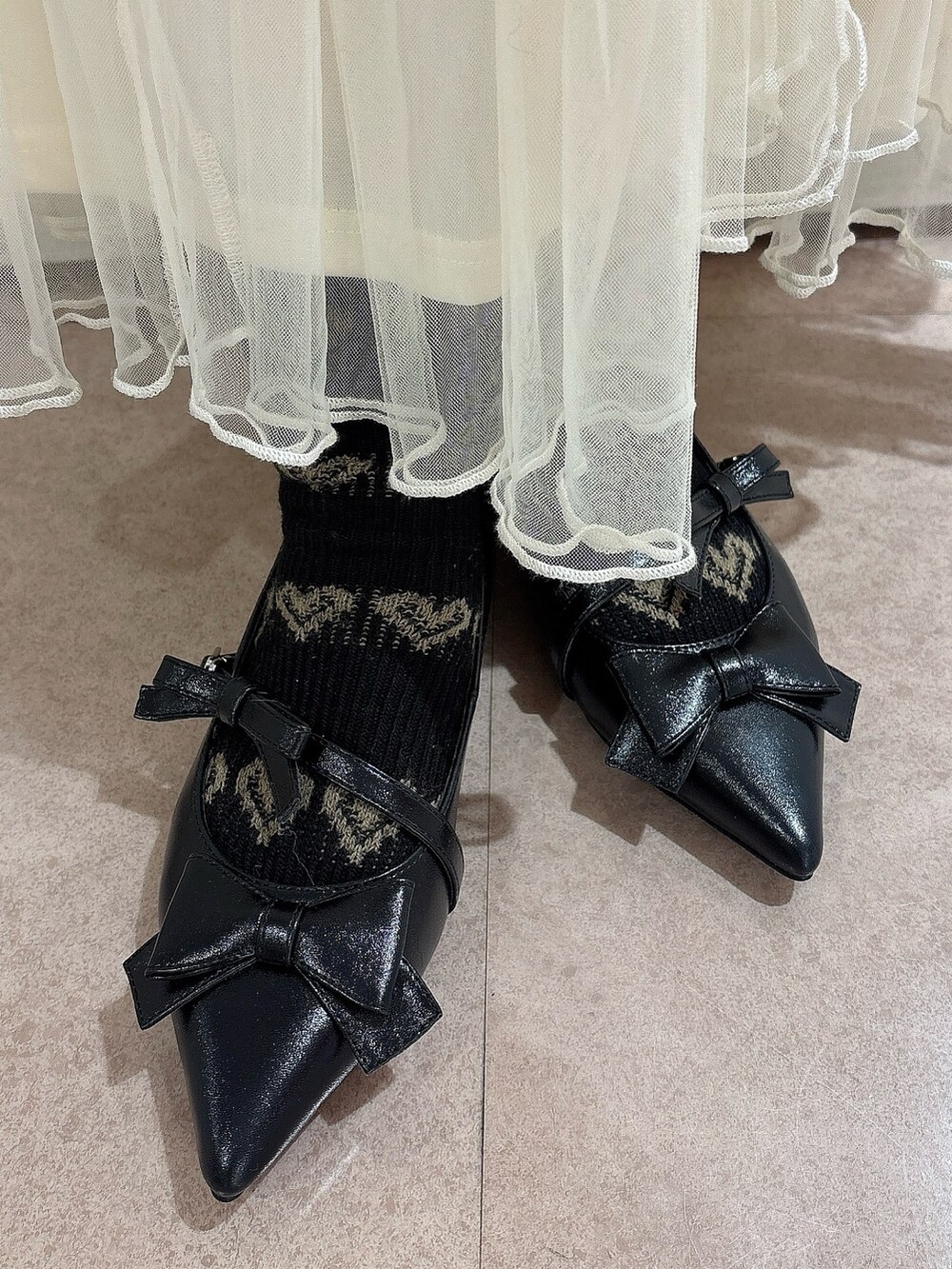 ブラック系のニット/セーター、レッド系のショルダーバッグ、ホワイト系のスカートを着用したレディースの冬コーディネートの8枚目の写真