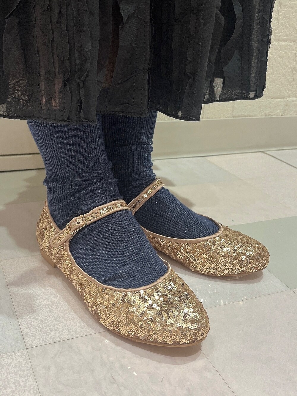 ブラック系のスカート、ゴールド系のパンプス、ホワイト系のTシャツ/カットソーを着用したレディースの夏コーディネートの4枚目の写真