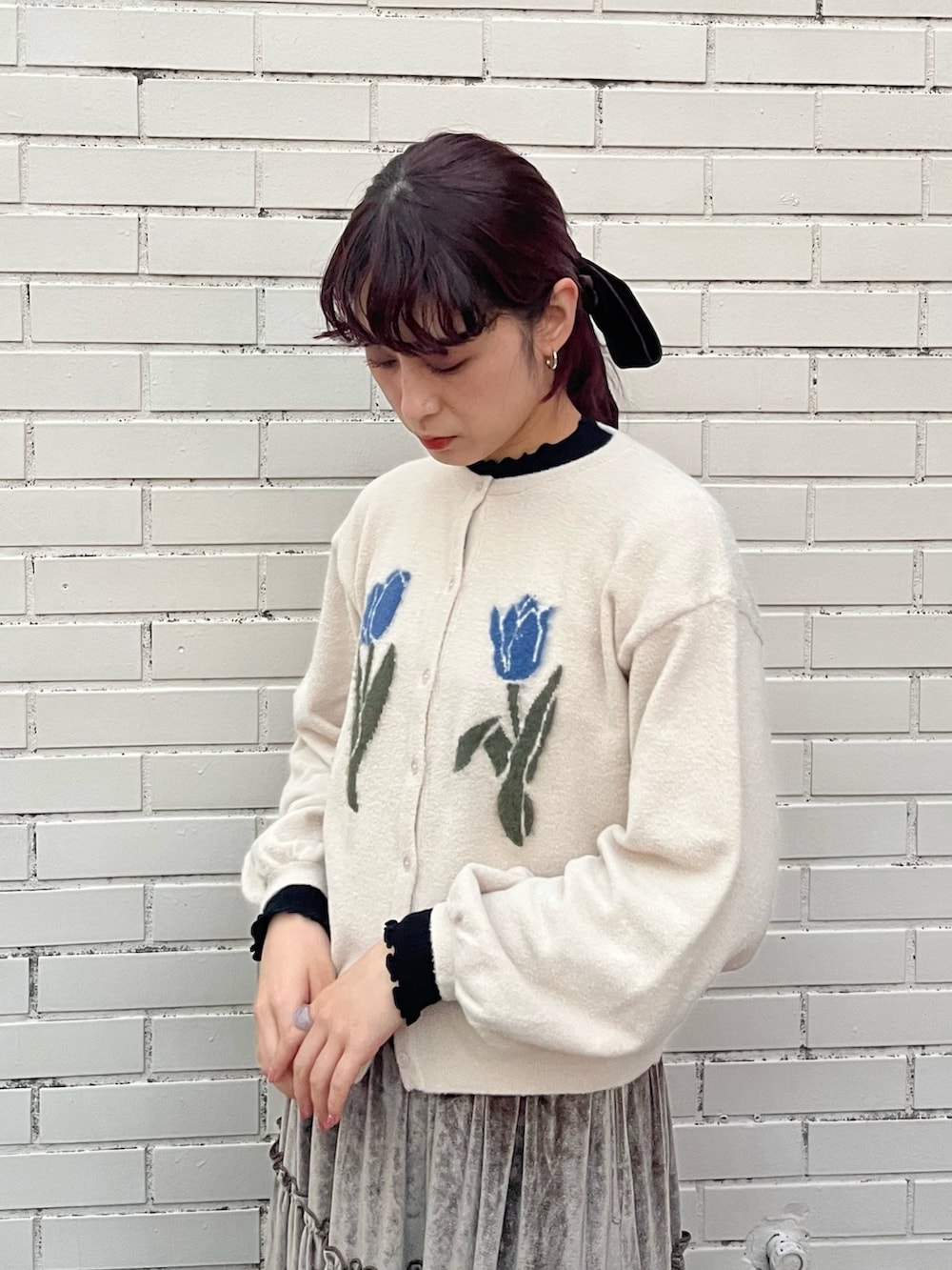 ブラウン系のスカート、ホワイト系のカーディガン/ボレロ、ブラック系のニット/セーターを着用したレディースの秋コーディネートの2枚目の写真