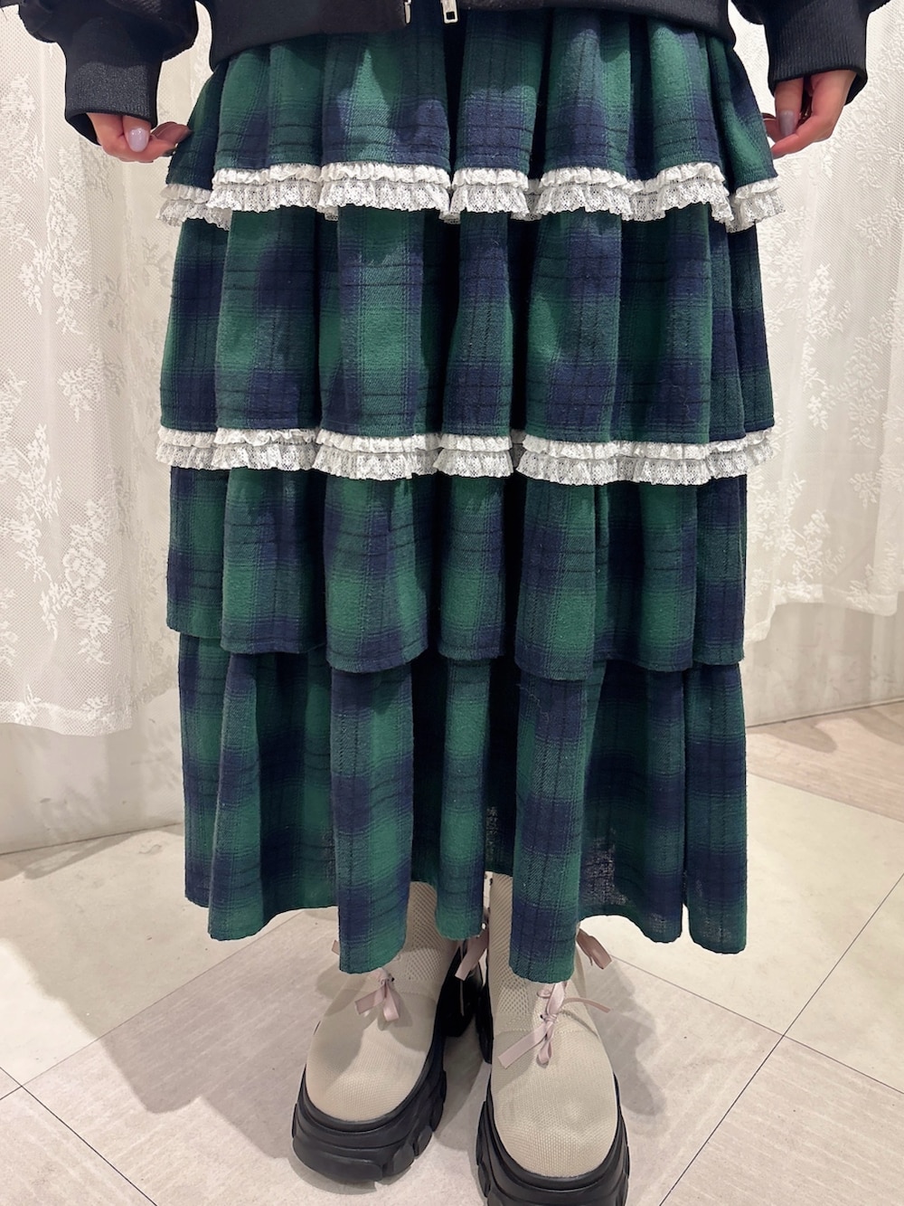 ブラック系のブルゾン、ホワイト系のニット/セーター、グリーン系のスカートを着用したレディースの秋コーディネートの6枚目の写真