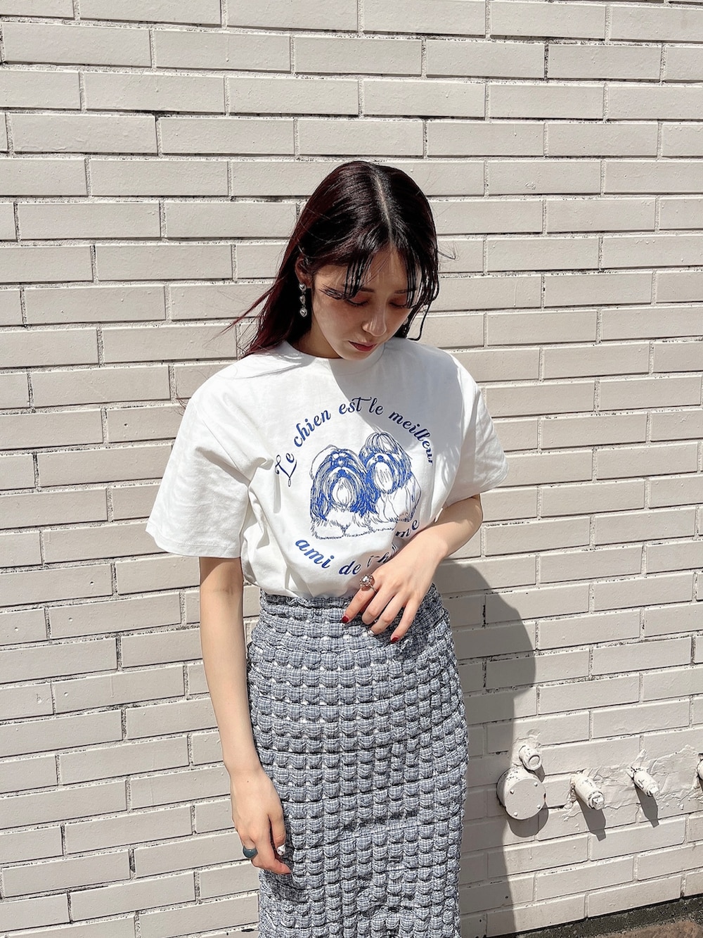 ブルー系のスカート、シルバー系のパンプス、ホワイト系のTシャツ/カットソーを着用したレディースの夏コーディネートの2枚目の写真