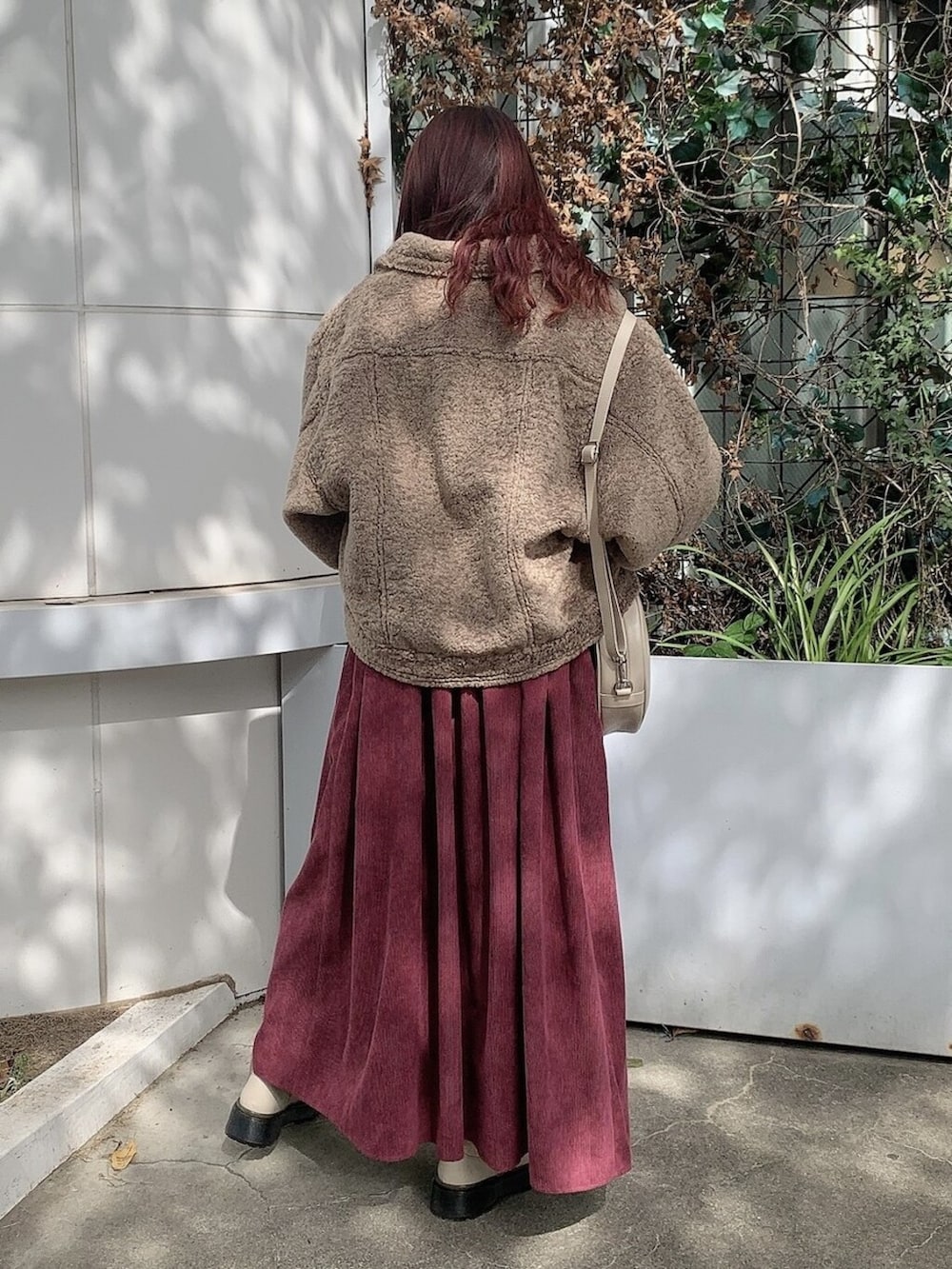 ブラウン系のカバーオール、ホワイト系のブーツ、ホワイト系のショルダーバッグを着用したレディースの秋コーディネートの3枚目の写真