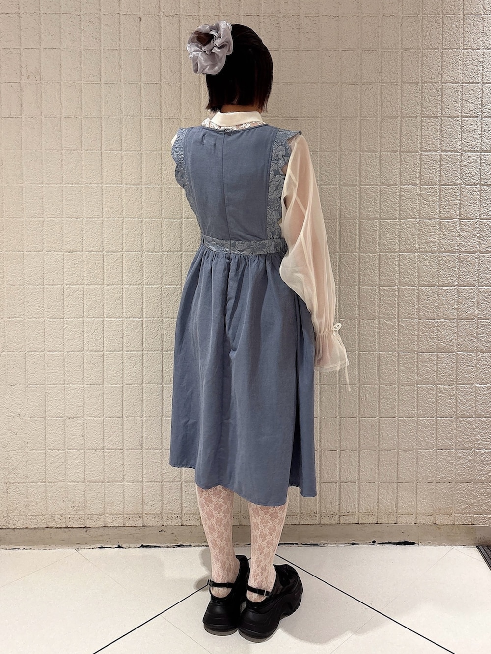 ブルー系のワンピース、ホワイト系のシャツ/ブラウス、ブラック系のスニーカーを着用したレディースの春コーディネートの2枚目の写真