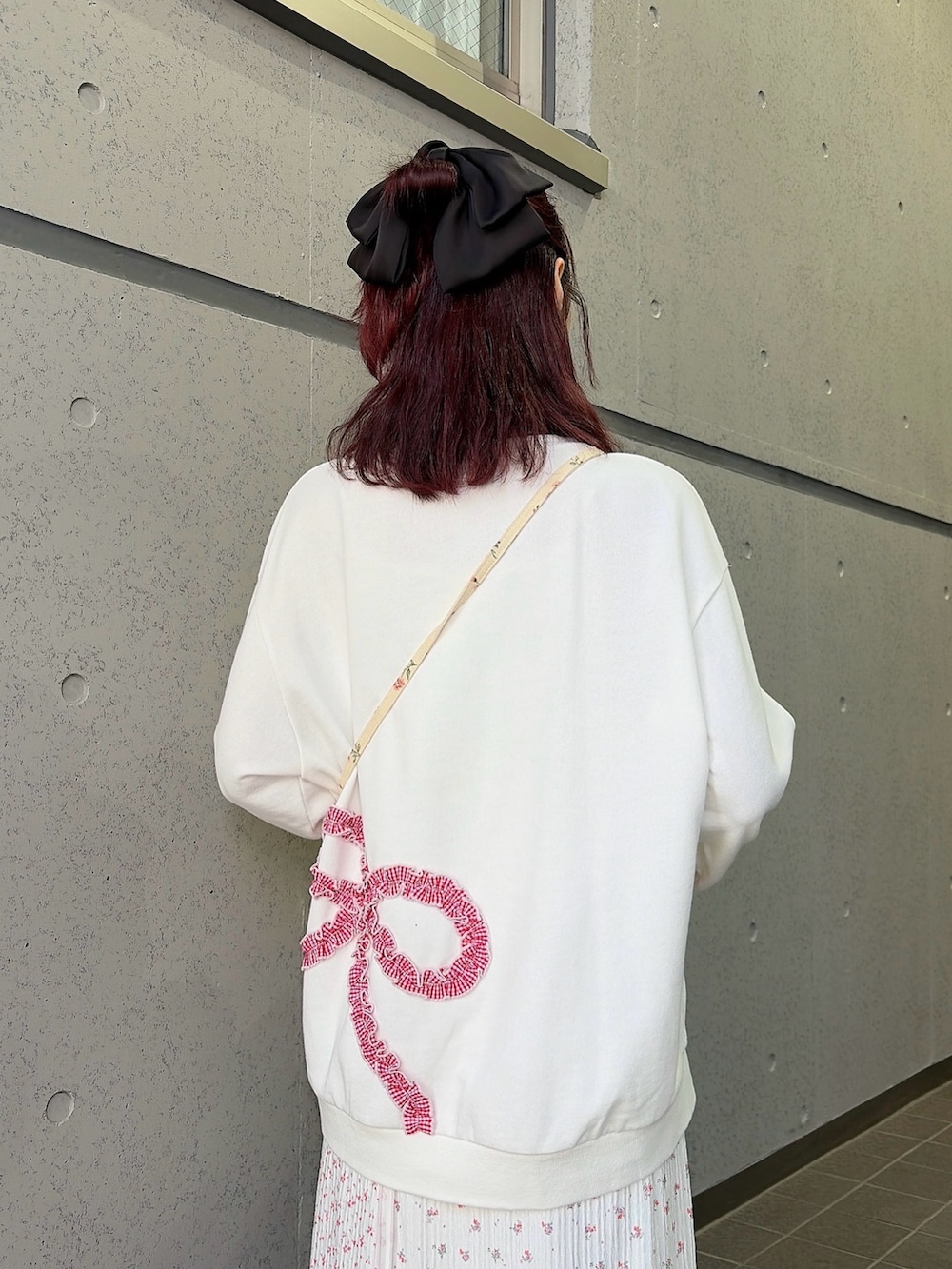 ホワイト系のスウェット、ホワイト系のショルダーバッグ、ピンク系のスカートを着用したレディースの冬コーディネートの4枚目の写真