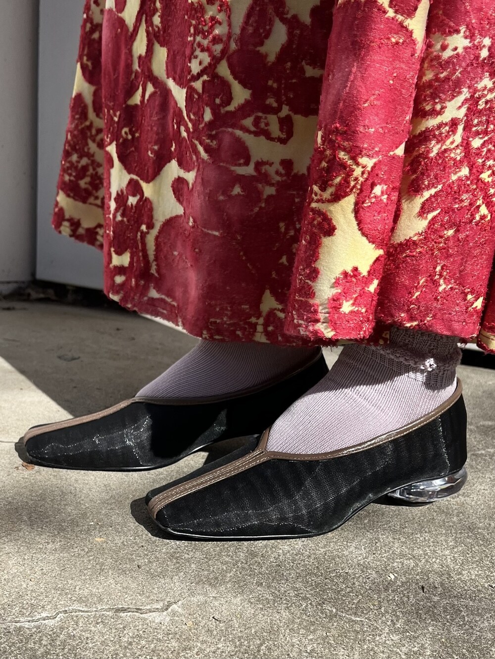 レッド系のワンピース、ブラック系のパンプス、ブラウン系のトートバッグを着用したレディースの冬コーディネートの3枚目の写真