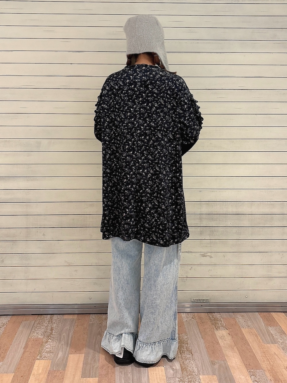 ブラック系のワンピース、ブルー系のデニムパンツ、ブラック系のスニーカーを着用したレディースの秋コーディネートの2枚目の写真