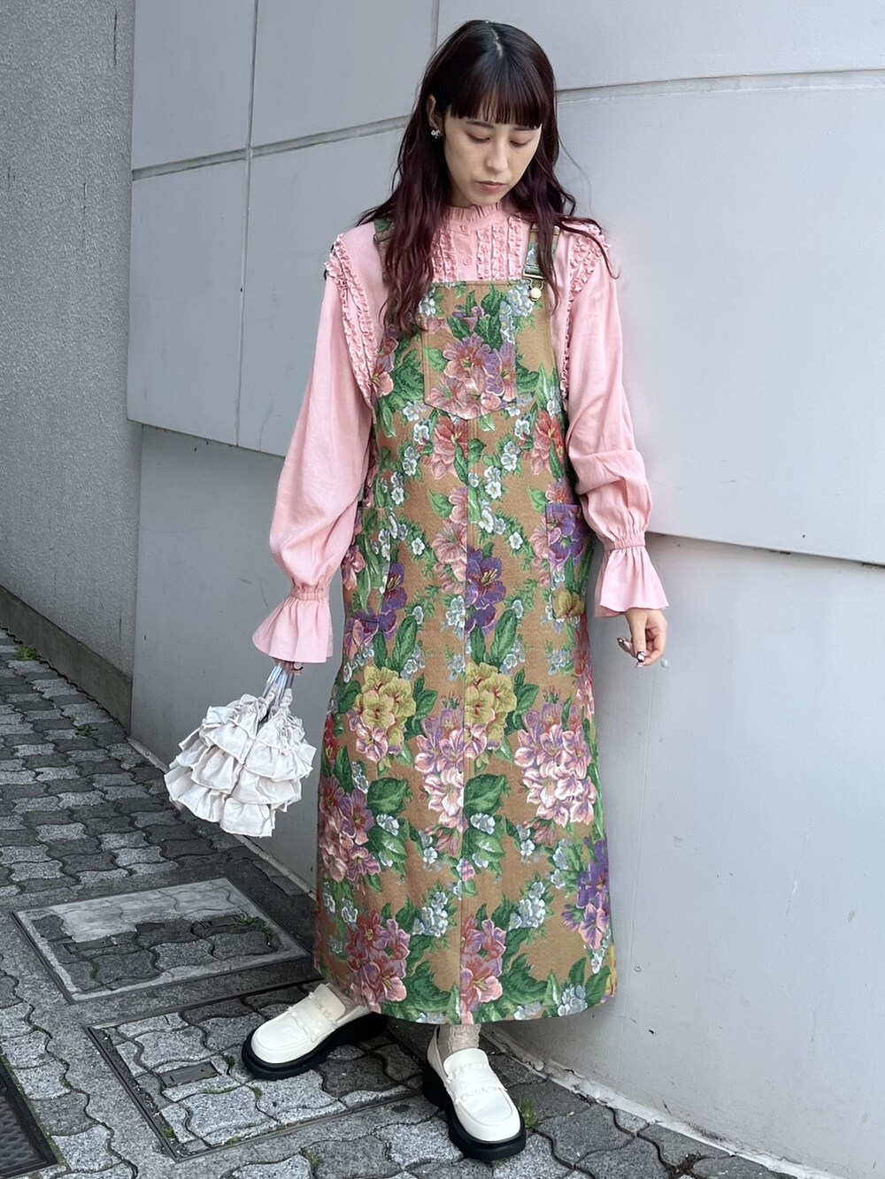 ピンク系のシャツ/ブラウス、ブラウン系のジャンパースカート、ホワイト系のハンドバッグを着用したレディースの春コーディネートの2枚目の写真