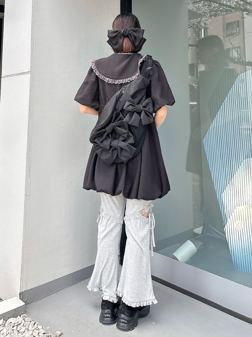 グレー系のスウェットパンツ、ブラック系のスニーカー、ブラック系のワンピースを着用したレディースの春コーディネートの2枚目の写真